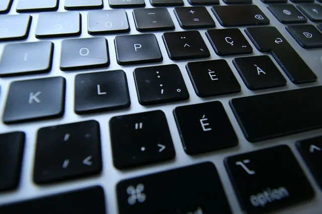Close-up of a silver laptop keyboard with black keys Zoomed in French Canadian « fr-CA » QWERTY keyboard characters, accents and punctuation touches. Bilingual Canadian SEO: French pages, hreflang, and provincial search intent