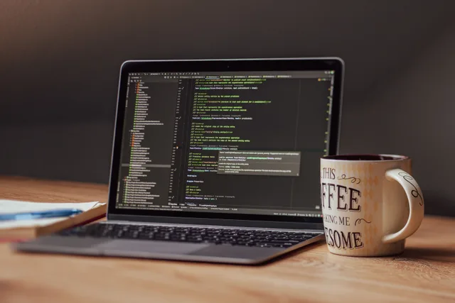 Laptop displaying code editor with coffee mug on desk, perfect for tech themes. On-page SEO questions business teams ask and what has no universal answer
