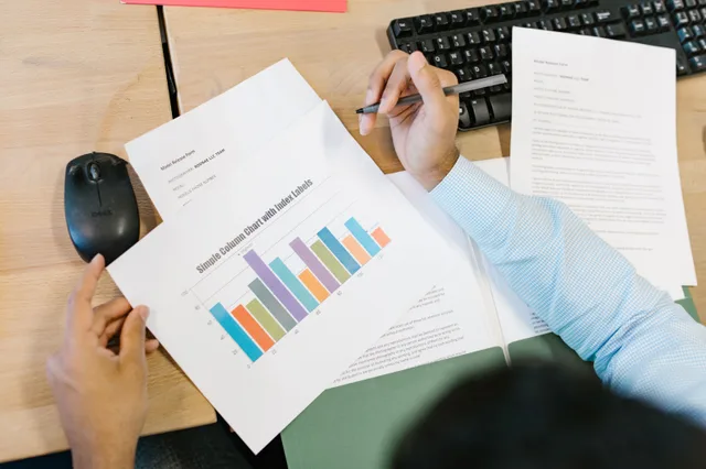 A business analyst reviews a colorful bar chart and documents at a desk, indicating data analysis. How to measure SEO analytics with defined populations and defensible baselines