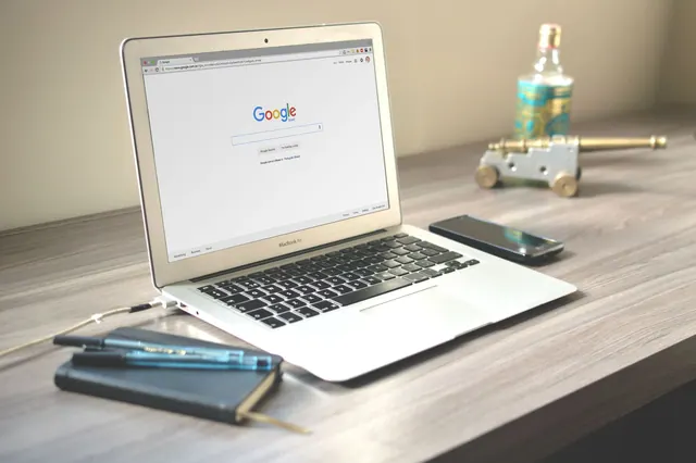 A neat workspace featuring a laptop displaying Google search, a smartphone, and a notebook on a wooden desk. Local SEO explained for business teams in 2027