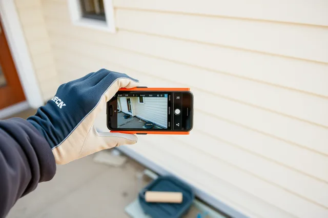 Painter photographing a freshly painted exterior wall with a smartphone. Painting contractor local SEO: the photo habit that separates real crews from the rest