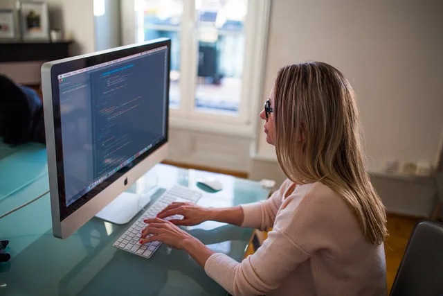 Seated Woman Typing on Apple Mighty Keyboard in Front of Turned-on Silver Imac. Working through the on-page SEO checklist in order