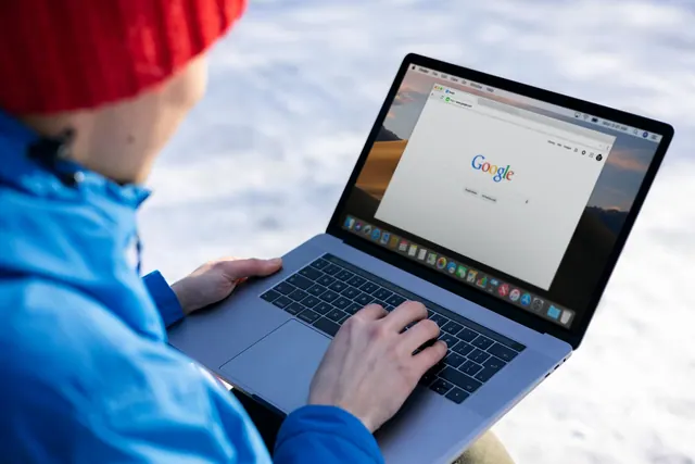 Person in winter gear using a laptop with a Google search on screen outdoors. The practical 2027 guide to SEO analytics