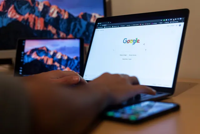 Hands typing on a laptop with Google on screen, in a remote work setup in Milan, Italy. Strategy mistakes in SEO: promising rankings still costs the most