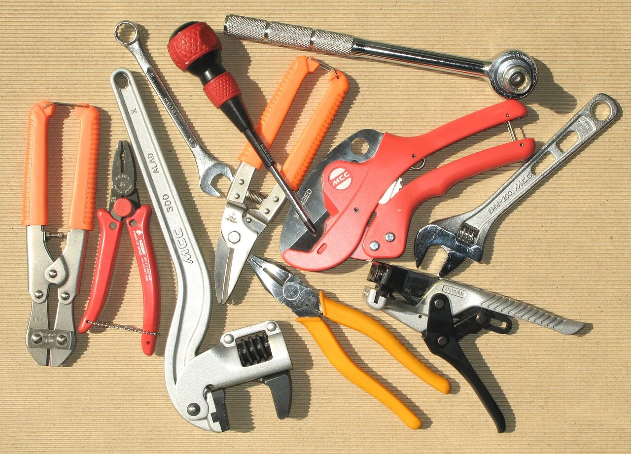 A collection of hand tools arranged on a wooden surface.